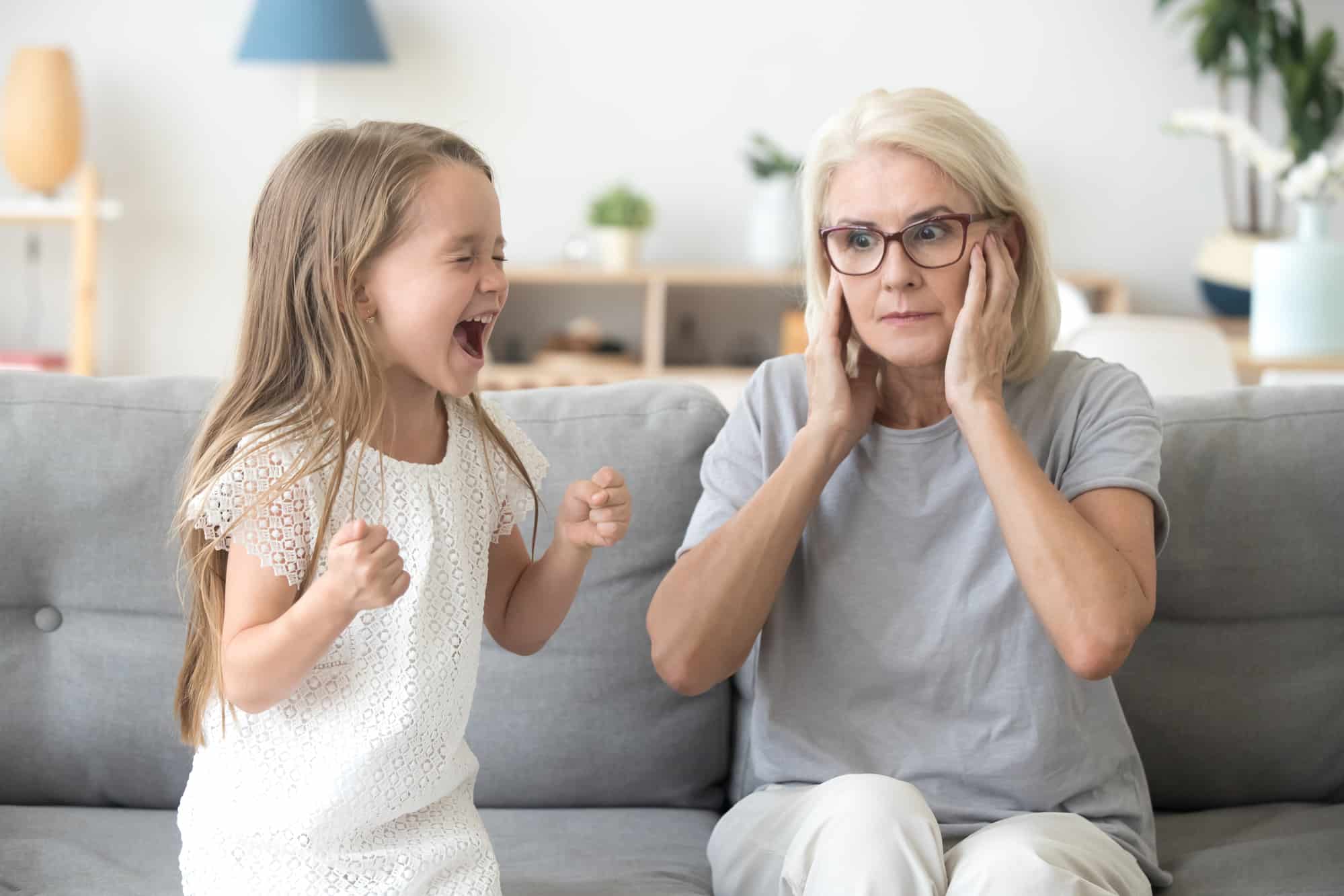 A grandma closing ears not to hear granddaughter with ADD screaming