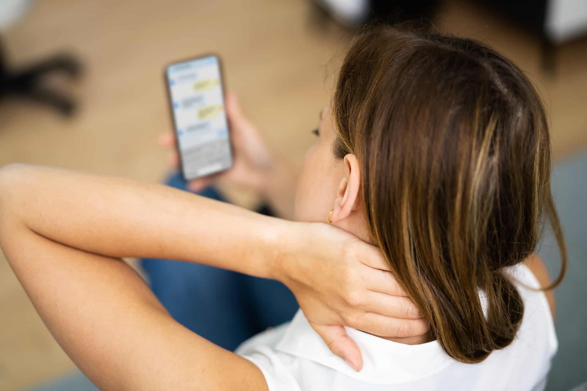 Woman With Neck Pain Sitting Using Mobile Phone