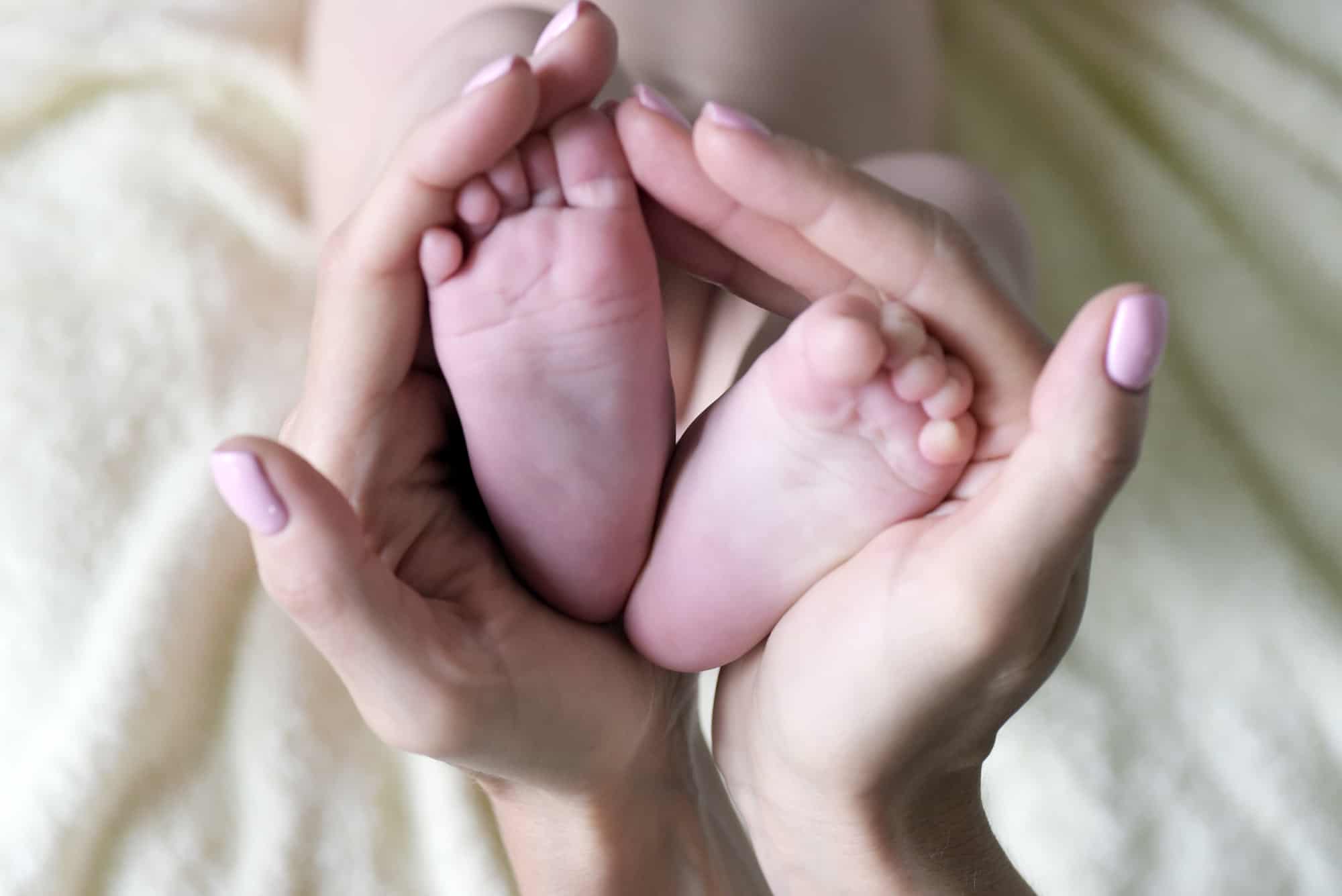 A new mom is holding her daughter's feet