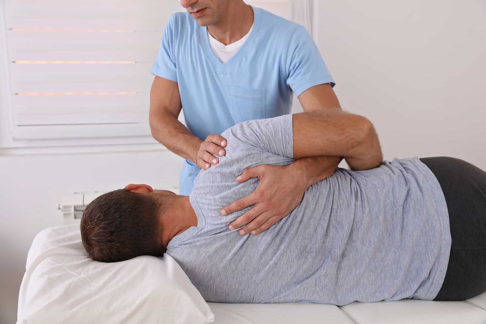 A man is receiving a massage from a chiropractor to address back pain