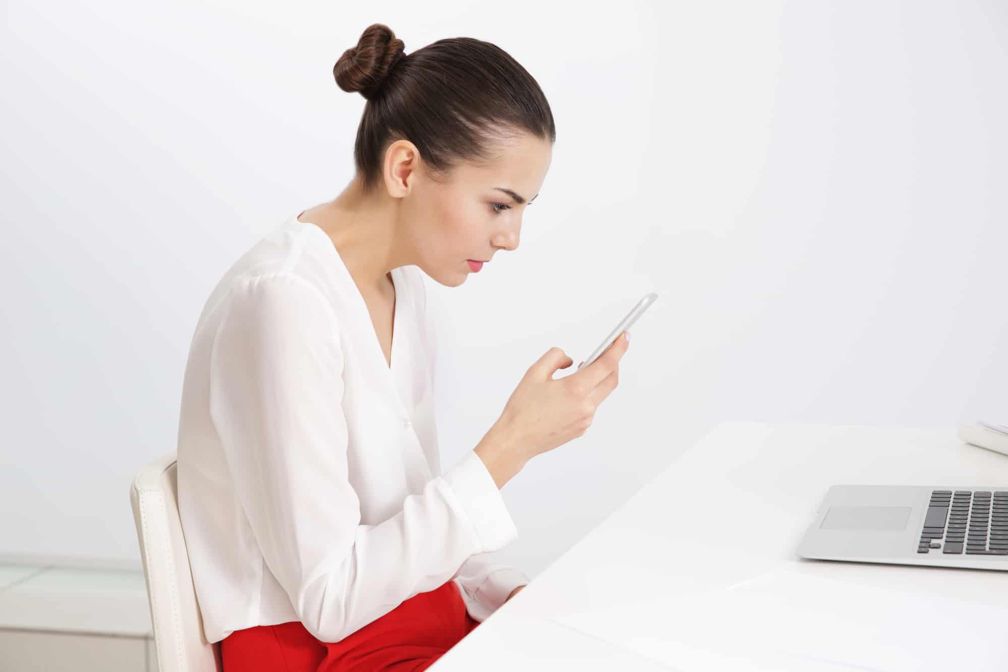 Young woman with phone sitting at table indoors