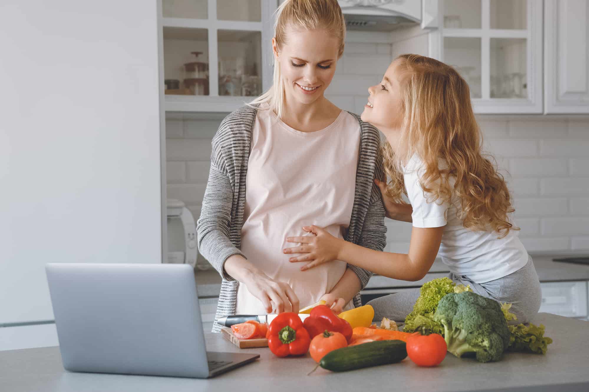 A pregnant mother and her daughter bonding in the kitchen