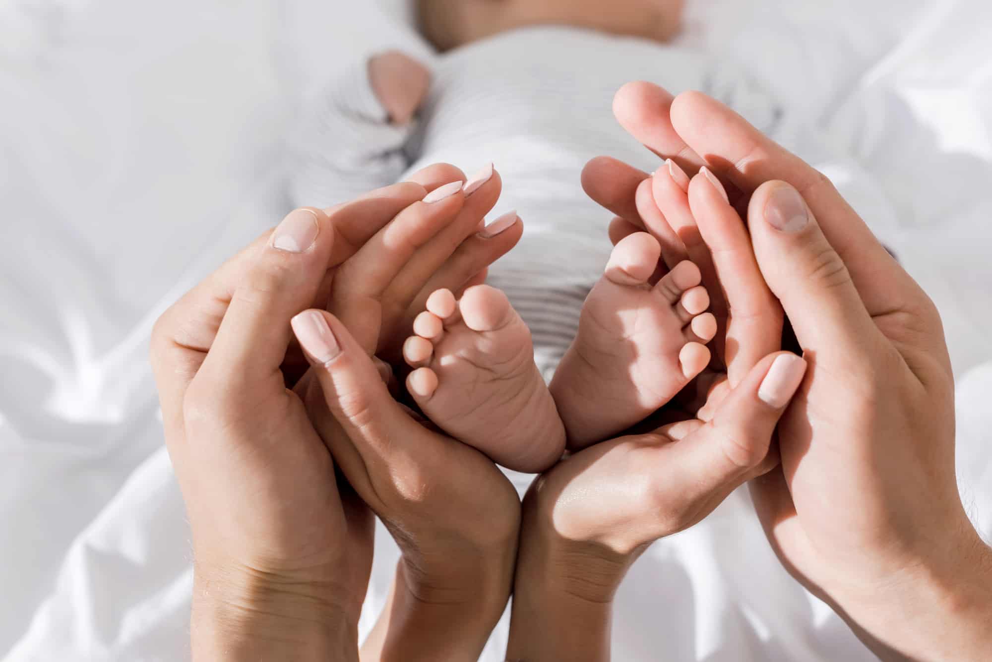 A photo capturing a mother holding the feet of her baby