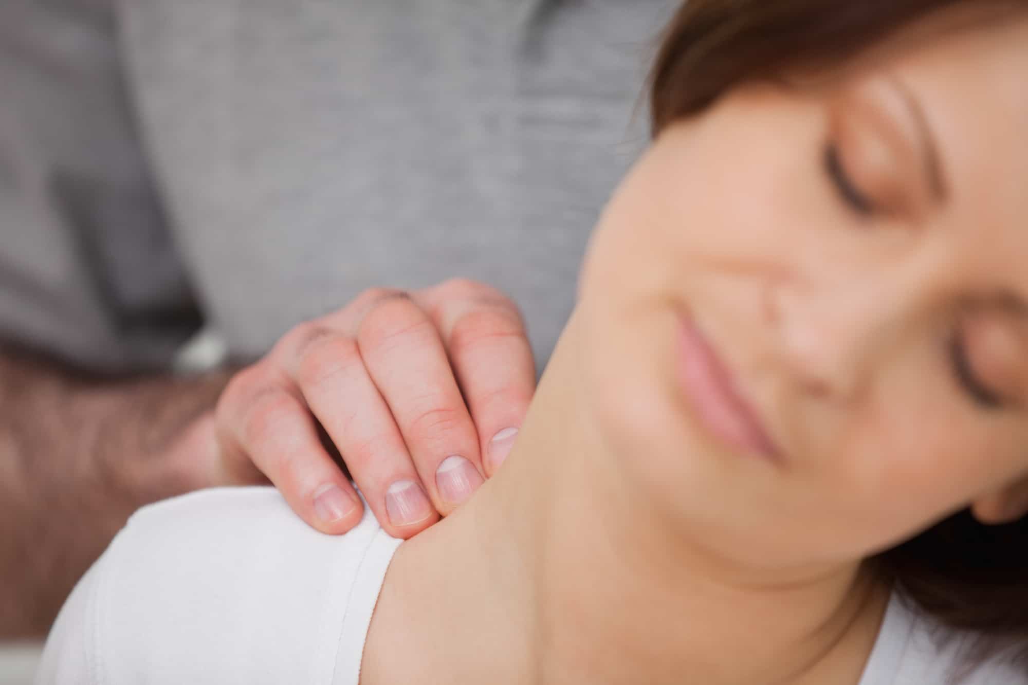 A woman is receiving a massage from a chiropractor for her neck pain