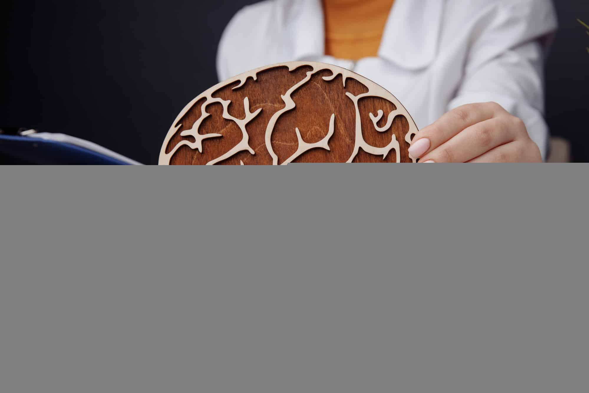 A chiropractor holding a wooden brain and explaining how chiropractic care can unlock brain power.