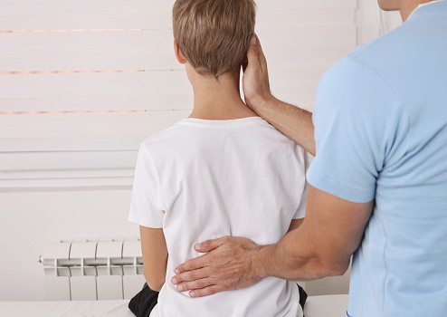 A young boy is receiving chiropractic treatment to address poor posture