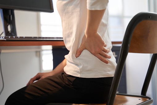 a woman suffering from lower back pain at work