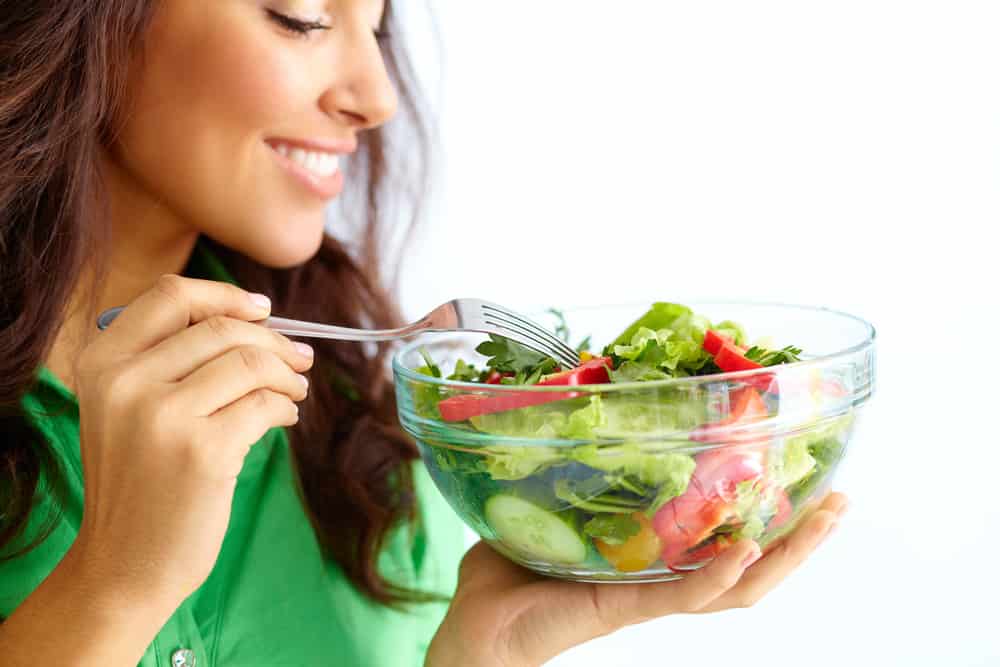 A woman is enjoying a healthy, nutritious vegetable salad