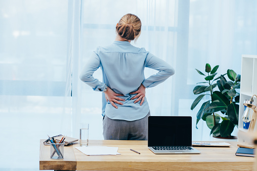 A woman experiencing back pain in the office